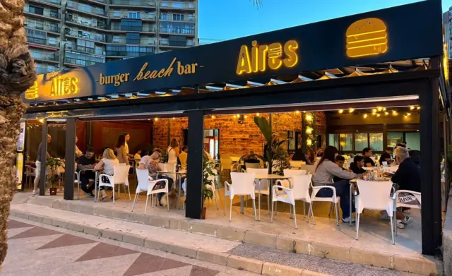 Terraza de Aires Burger Bar Arenales del Sol frente al local iluminado