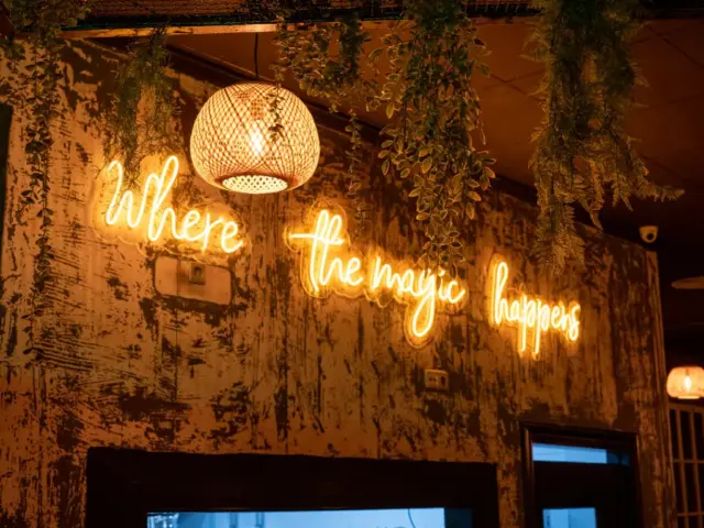 Pared del restaurante Aires Burger Bar Orihuela con un mensaje de neón y una lámpara