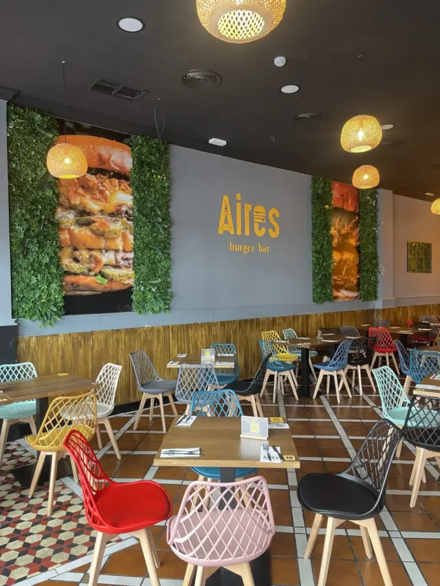 Interior de Aires Burger Bar Murcia Thader con mesas, sillas y rótulo Aires