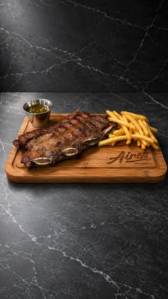 Asado de tira a la brasa con patatas fritas sobre una tabla de madera