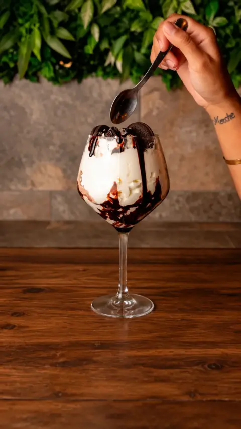 Postre Bombaires en una copa con helado y chocolate vertido por encima