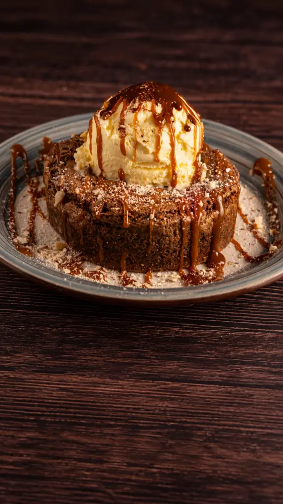 Brownie casero con una bola de helado y salsa de chocolate