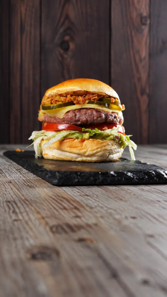 Hamburguesa Carlota con lechuga y tomate sobre una superficie oscura