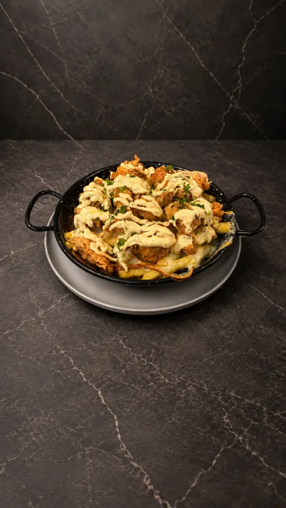 Patatas con pollo, salsa y hierbas servidas en una cazuela