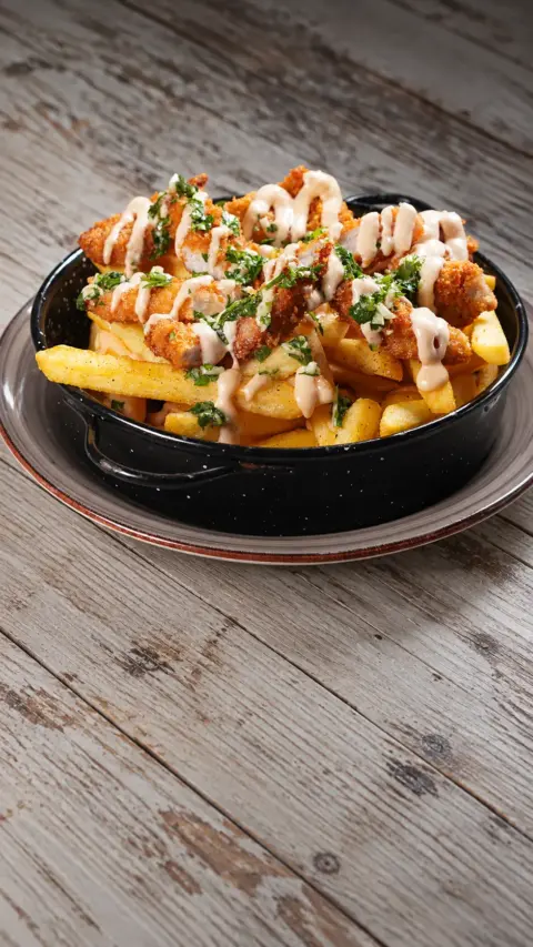 Patatas fritas con pollo crujiente, salsa y hierbas
