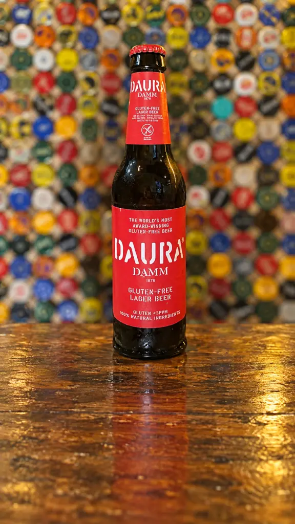 Botella de cerveza Daura con etiqueta roja