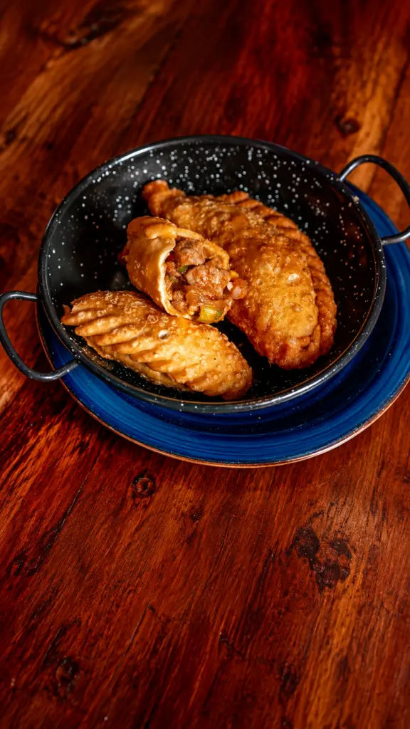 Empanadas argentinas fritas, una de ellas abierta para mostrar el relleno