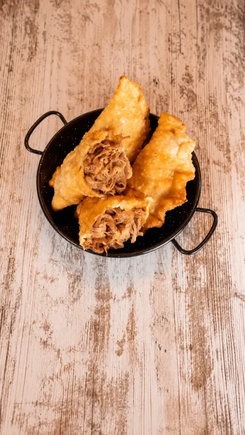 Empanadas abiertas con relleno de carne deshilachada en una cazuela