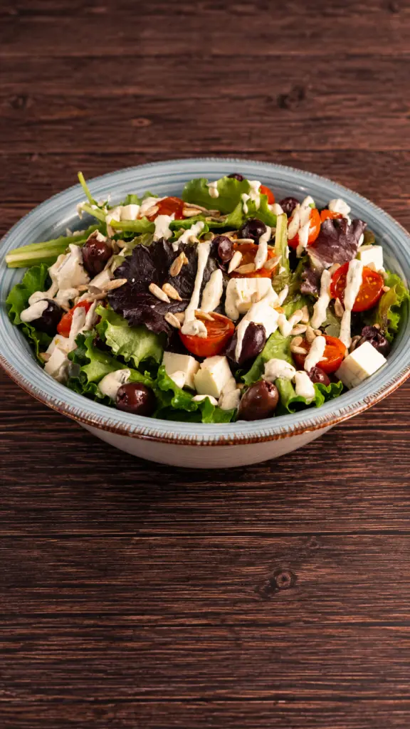 Ensalada griega con hojas verdes, tomate, aceitunas y queso