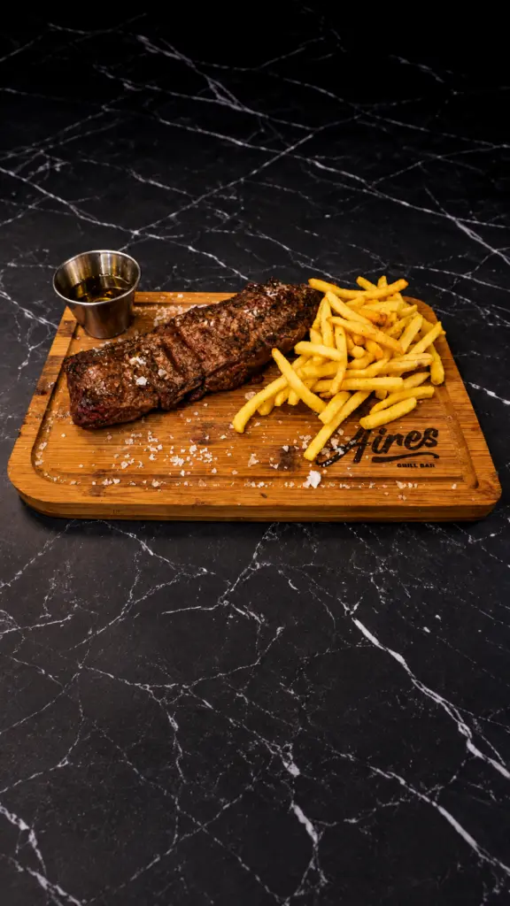 Entraña a las brasas con patatas fritas sobre una tabla de madera