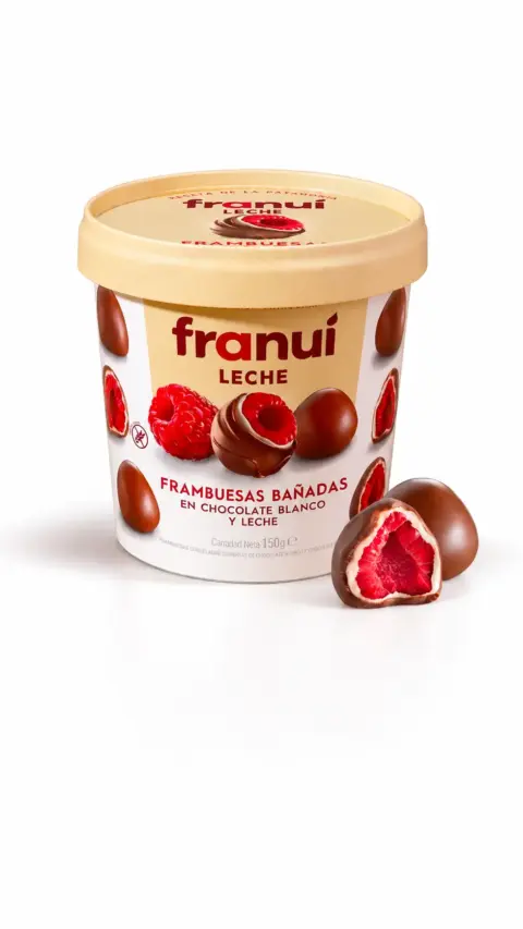 Envase de Franuí de chocolate con leche junto a una frambuesa cubierta de chocolate