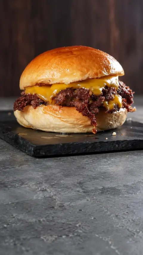Hamburguesa HDP con carne y queso fundido sobre fondo oscuro