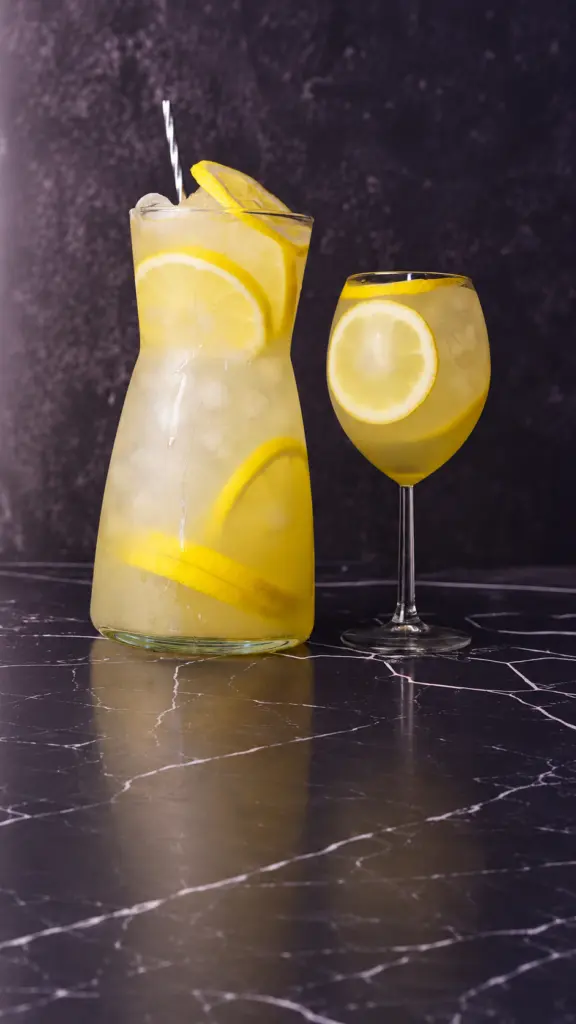 Jarra y copa de limonada clásica con rodajas de limón