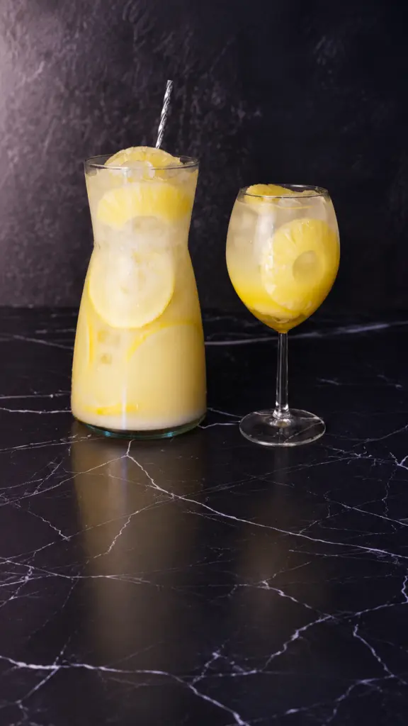 Jarra y copa de limonada de coco y piña con hielo