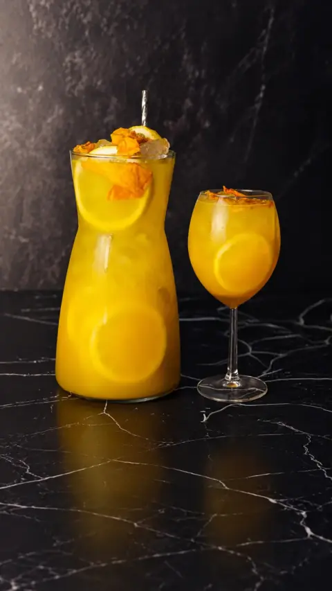 Jarra y copa de limonada de mango y maracuyá con hielo
