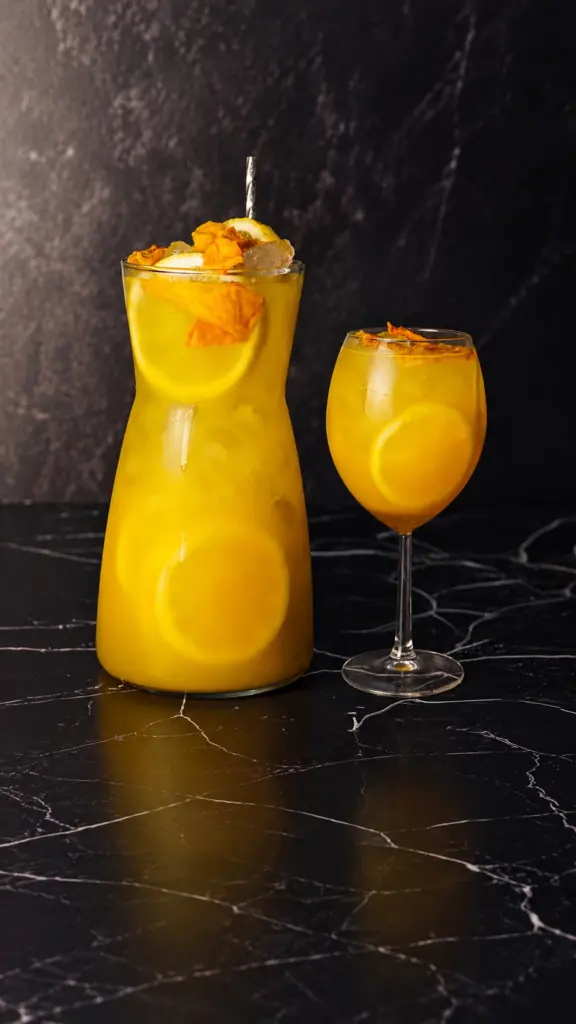 Jarra y copa de limonada de mango y maracuyá con hielo