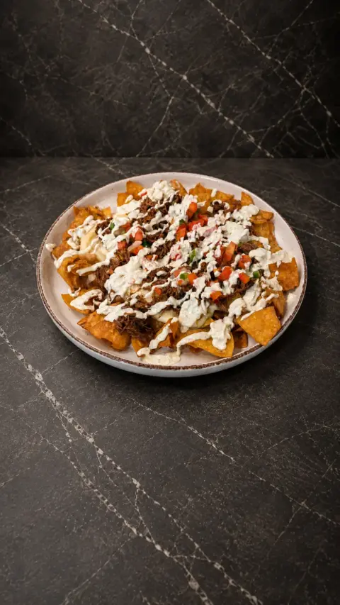 Nachos Poronga con carne y salsas servidos en un plato