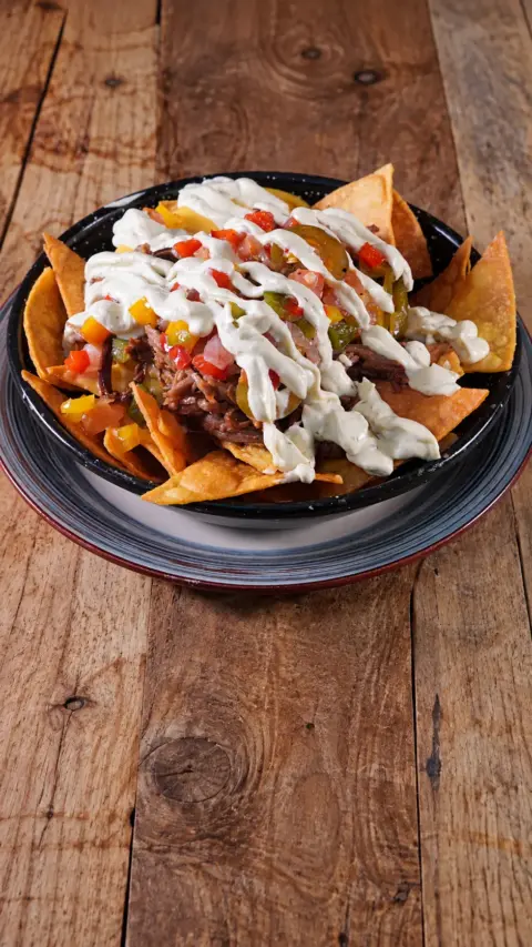 Nachos Poronga con carne y salsas servidos en una cazuela