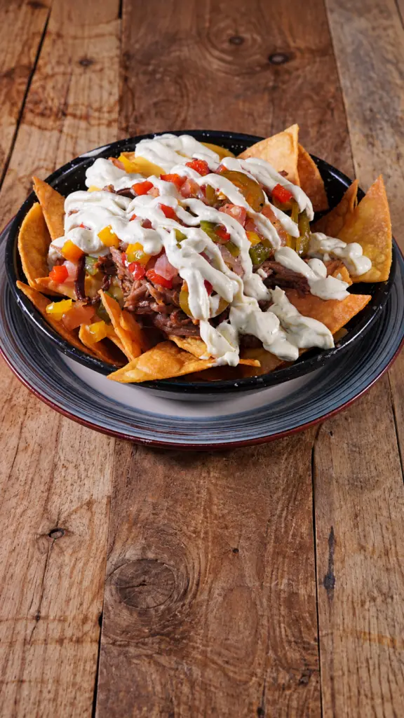 Nachos Poronga con carne y salsas servidos en una cazuela