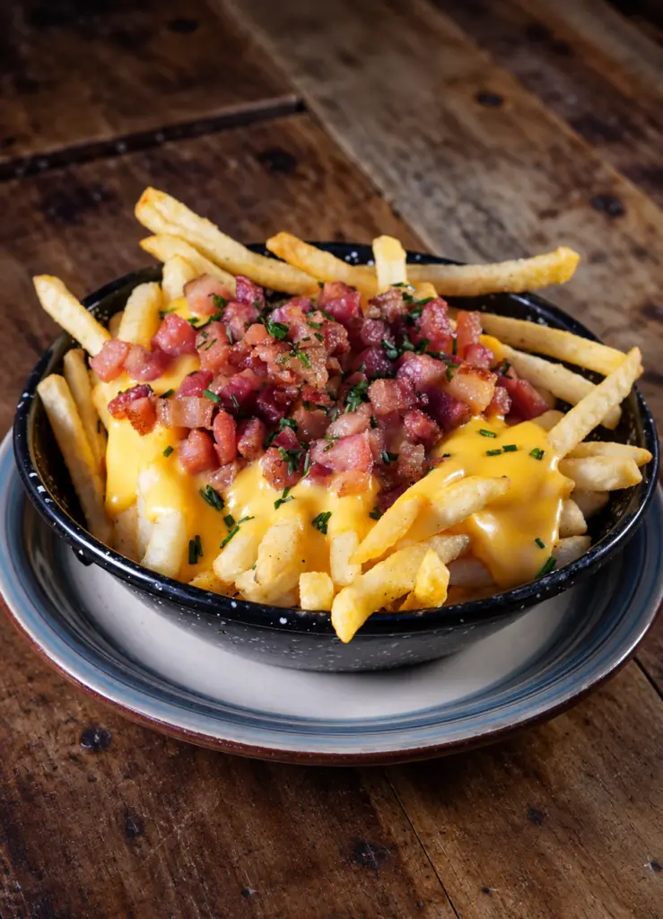 Patatas fritas con cheddar, dados de bacon y hierbas