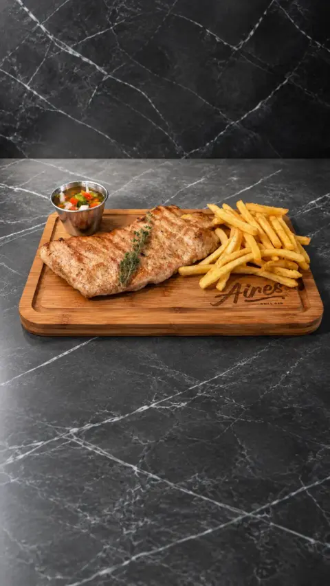Secreto ibérico a la brasa con patatas fritas sobre una tabla