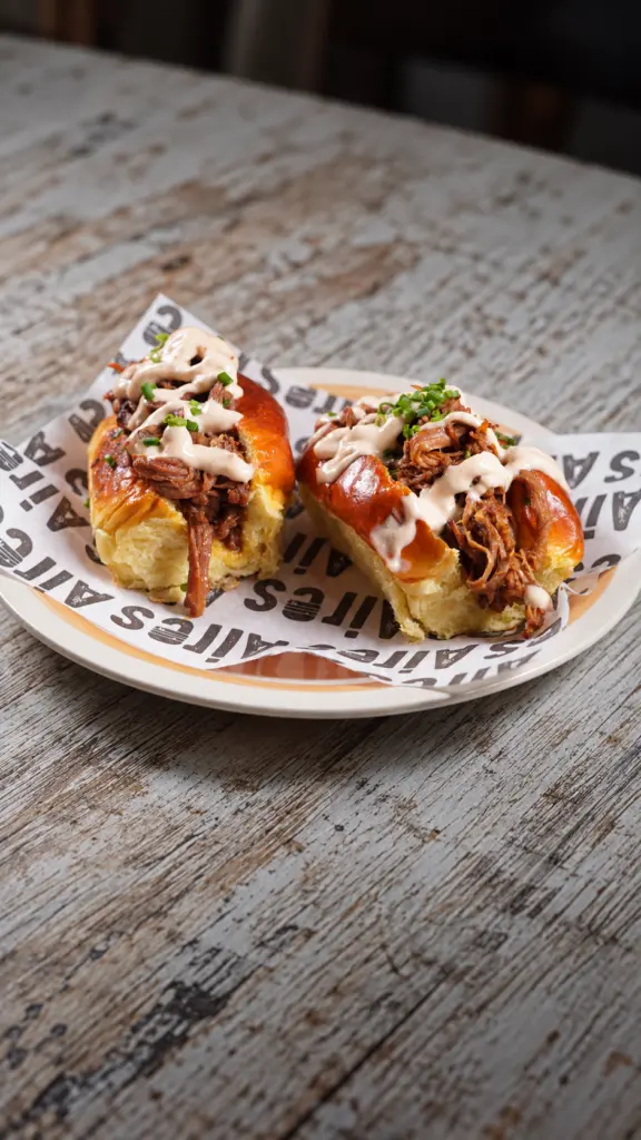 Dos panes rellenos de carne deshilachada con salsa y hierbas